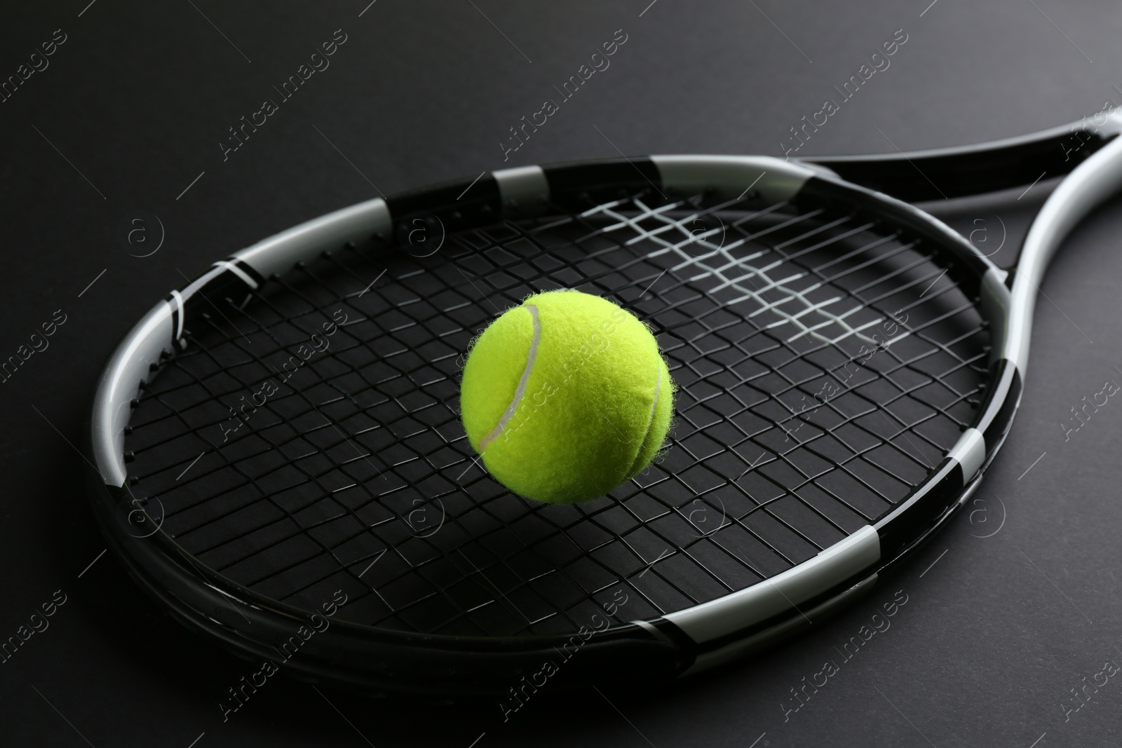 Photo of Tennis racket and ball on black background. Sports equipment