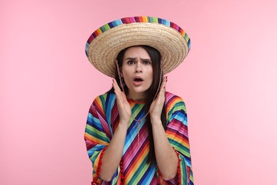 Photo of Surprised woman in Mexican sombrero hat and poncho on pink background