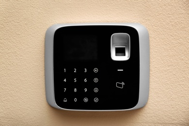 Modern alarm system with fingerprint scanner on color wall