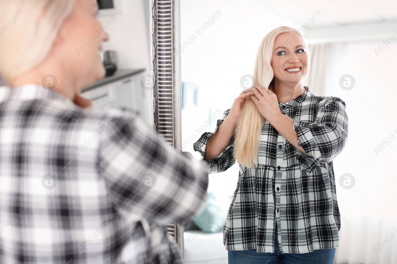 Photo of Mature woman looking in mirror at home