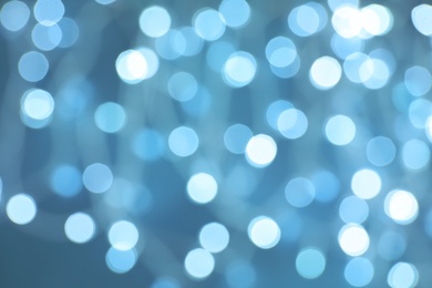 Blurred view of Christmas lights on color background