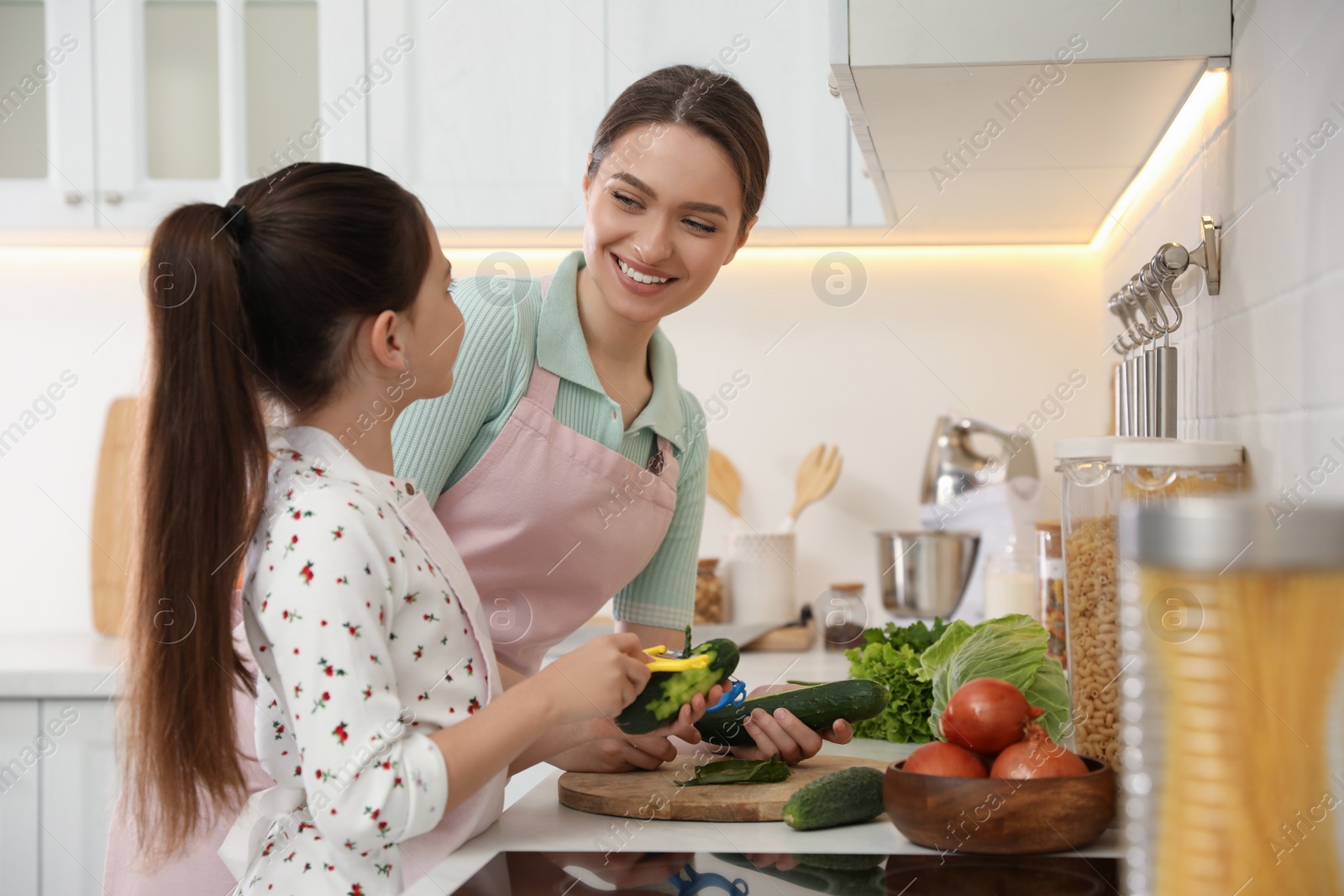 Photo of Mother and daughter peeling vegetables at kitchen counter