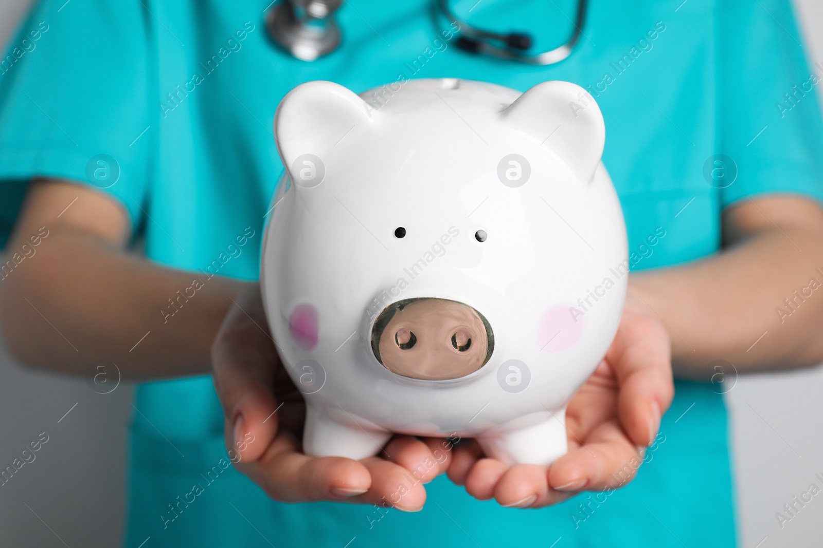 Photo of Doctor holding white ceramic piggy bank, closeup. Medical insurance