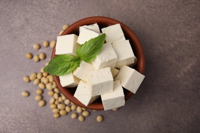 Delicious tofu cheese, basil and soybeans on brown textured table, flat lay