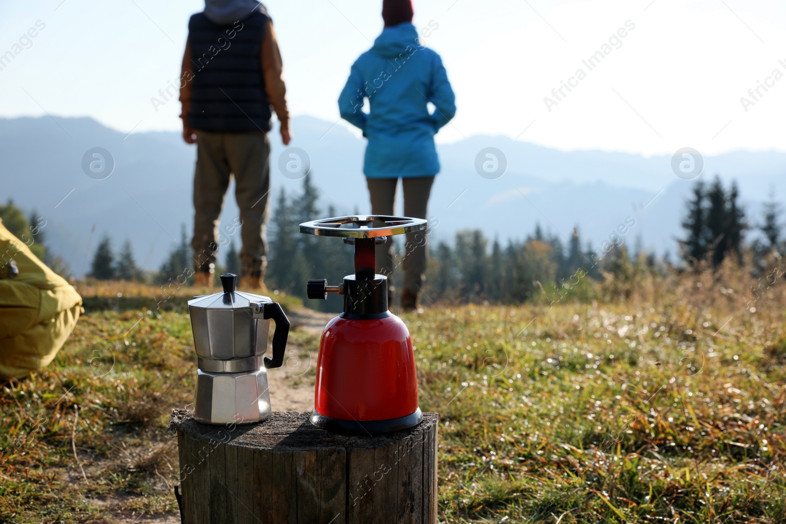 Photo of Couple enjoying beautiful mountain landscape in camping, focus on burner and moka pot