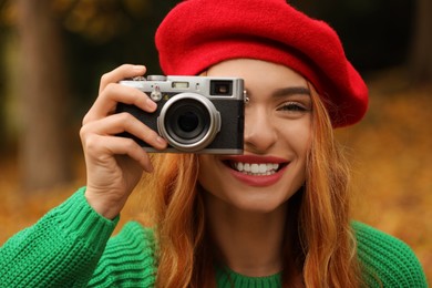 Photo of Smiling woman with camera taking photo in autumn park