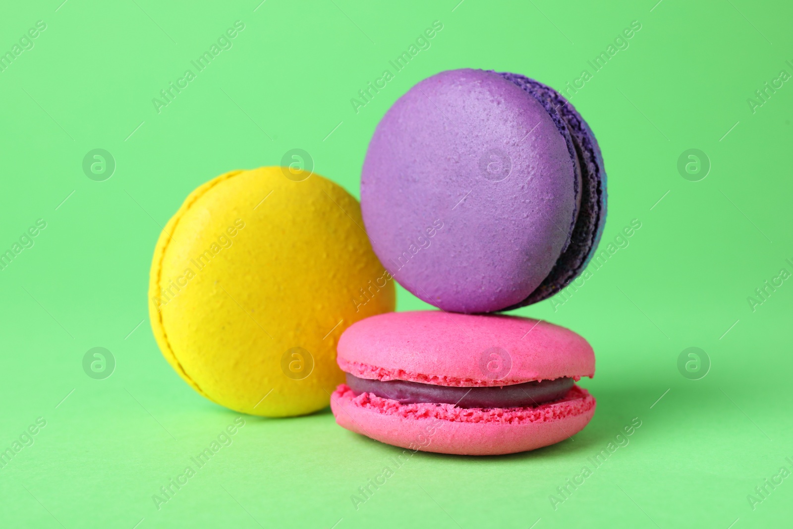Photo of Delicious colorful macarons on green background, closeup