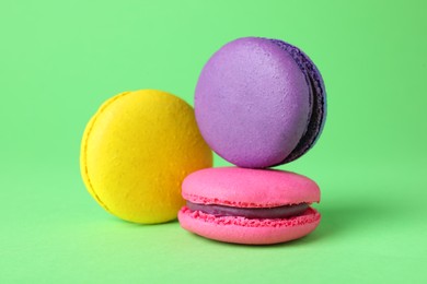 Photo of Delicious colorful macarons on green background, closeup