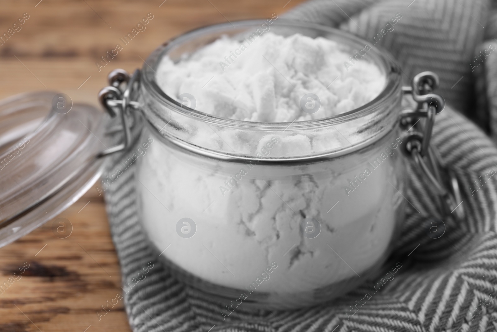 Photo of Glass jar of natural starch on wooden table, closeup