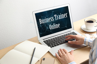 Image of Woman working with laptop at table indoors, closeup. Business trainer online