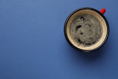 Photo of Fresh coffee in cup on blue background, top view. Space for text