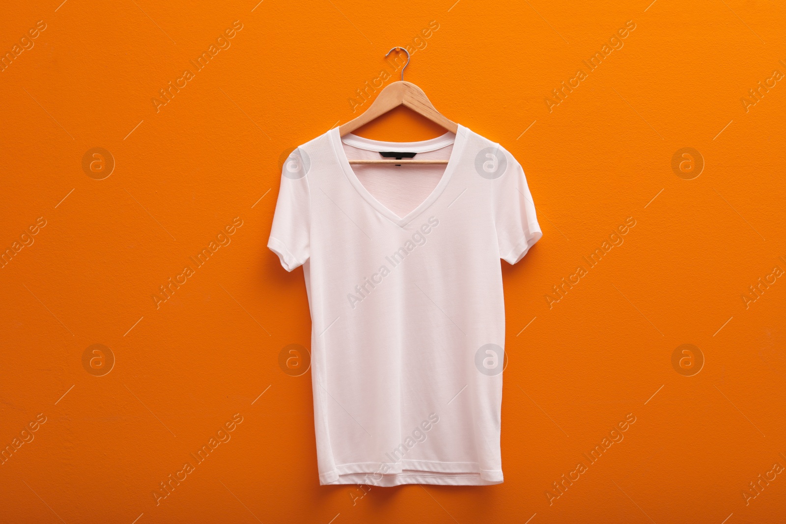 Photo of Hanger with blank t-shirt on color background. Mockup for design