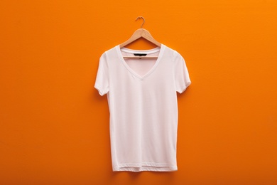 Photo of Hanger with blank t-shirt on color background. Mockup for design