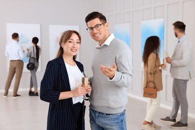 Photo of Couple with glass of champagne at exhibition in art gallery