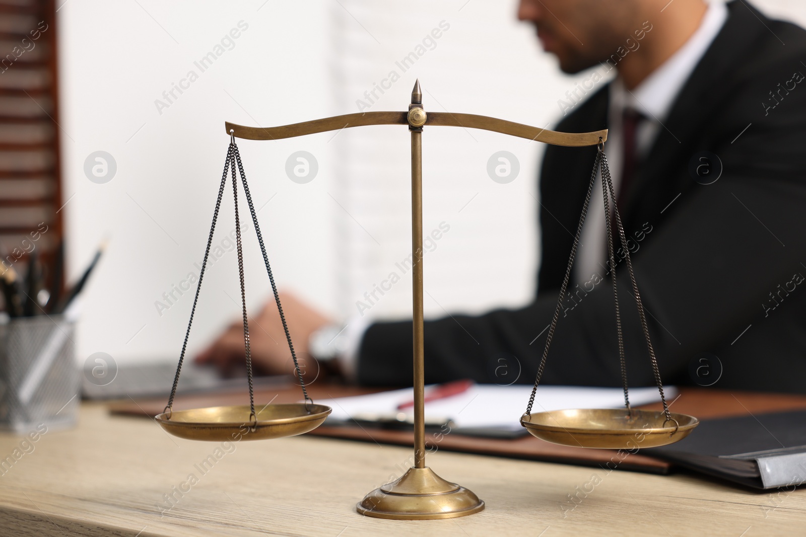 Photo of Lawyer working at table in office, focus on scales of justice