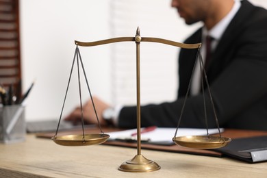 Photo of Lawyer working at table in office, focus on scales of justice