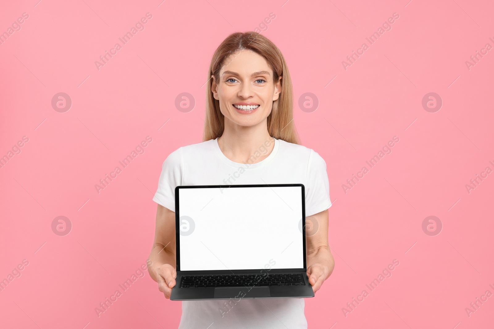 Photo of Happy woman showing laptop on pink background