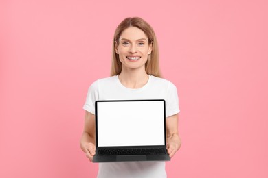 Photo of Happy woman showing laptop on pink background