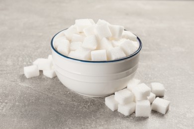 Photo of Bowl with sugar cubes on grey table, closeup