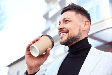 Photo of Businessman with cup of coffee on city street in morning