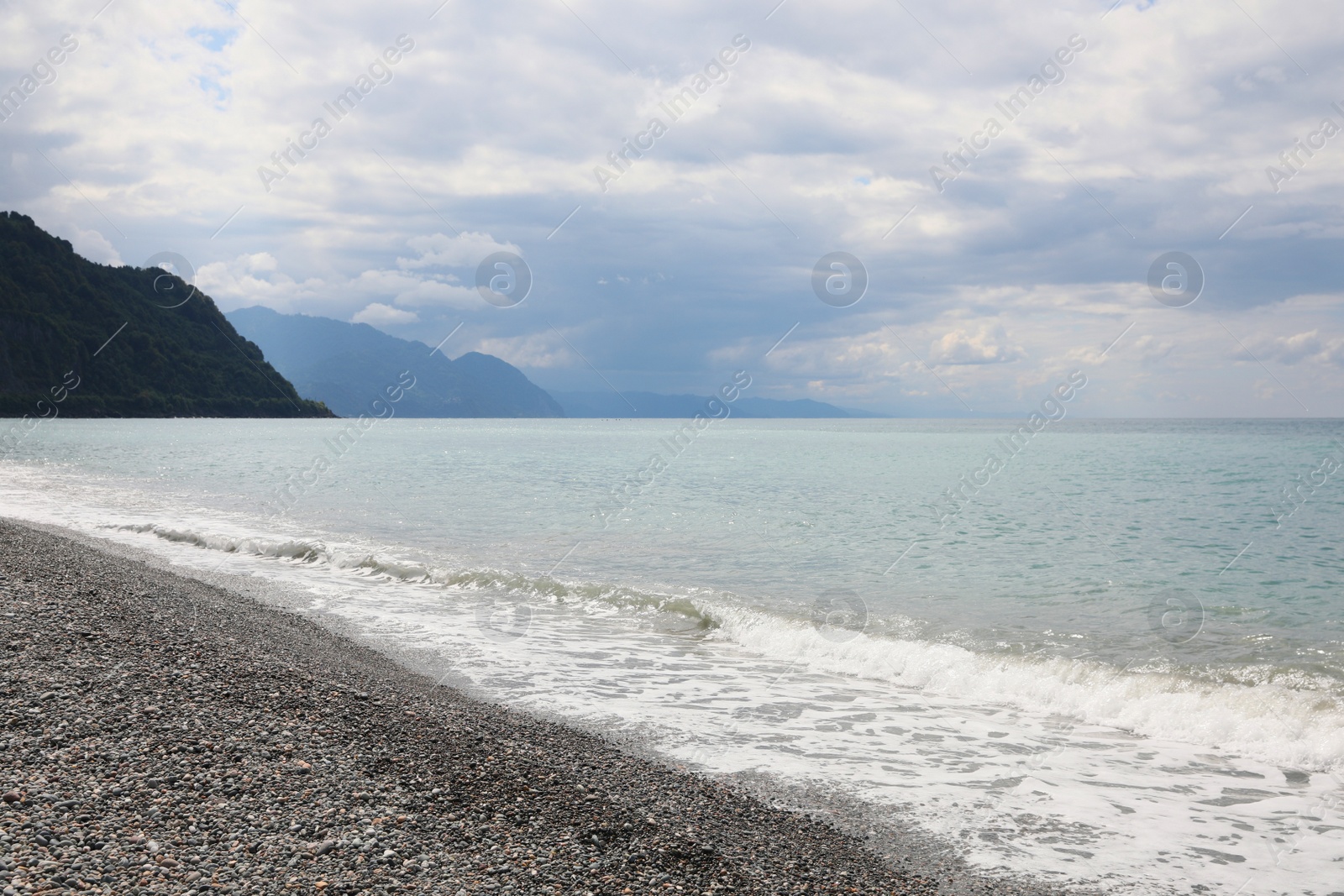 Photo of Picturesque view of beautiful sea shore and hills under sky with fluffy clouds