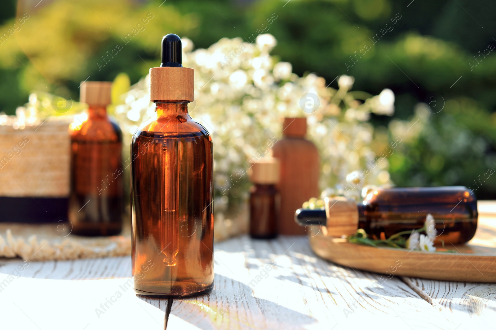 Photo of Bottle of chamomile essential oil on white wooden table, space for text