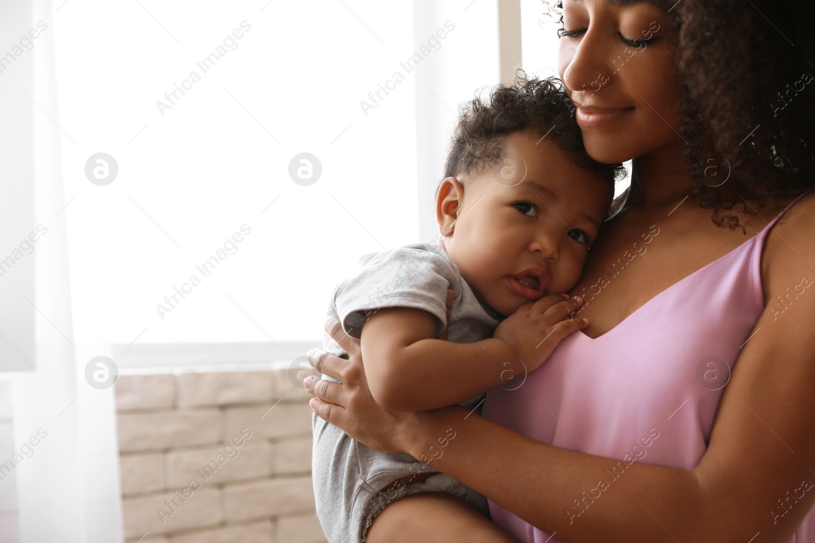 Photo of African-American woman with her baby at home. Happiness of motherhood