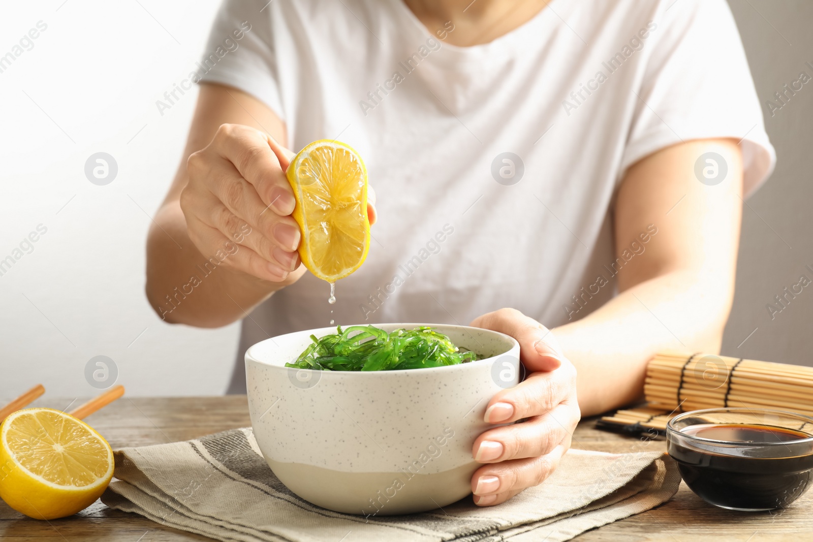 Photo of Woman eating Japanese seaweed salad at table, closeup