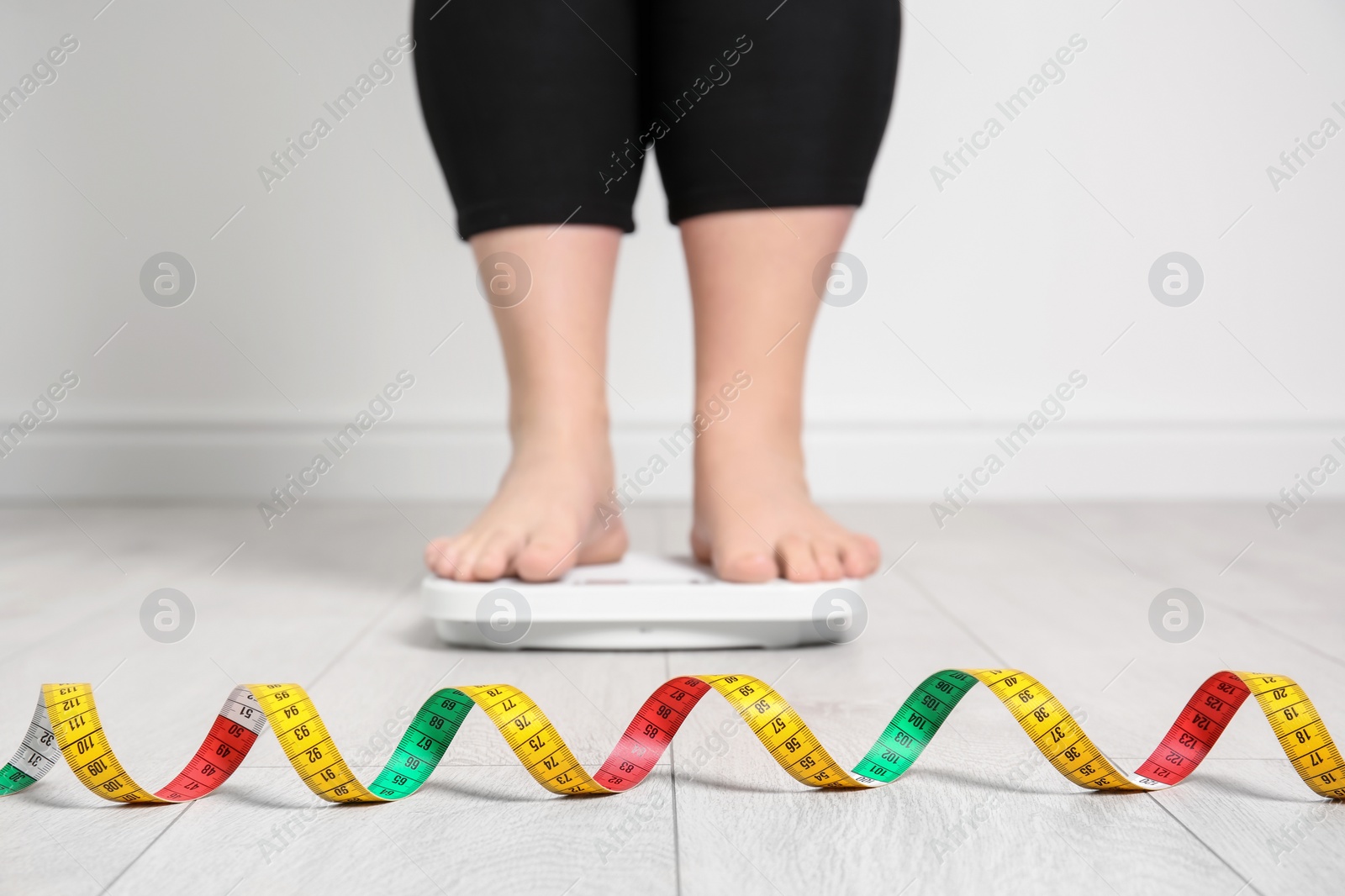 Photo of Overweight woman using scales indoors