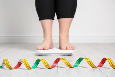 Photo of Overweight woman using scales indoors