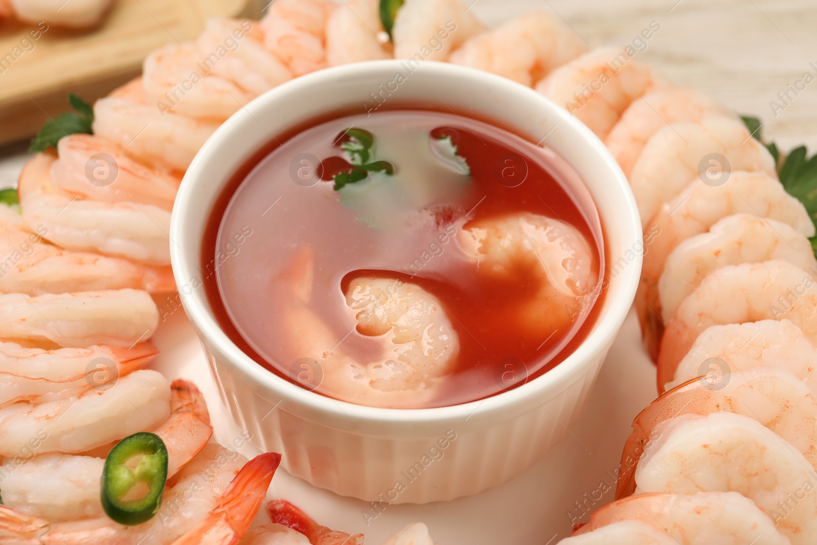 Photo of Tasty boiled shrimps with cocktail sauce, chili and parsley on table, closeup