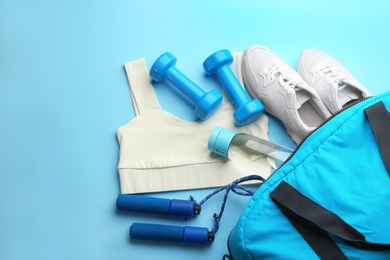 Composition with gym bag and sports items on light blue background, above view