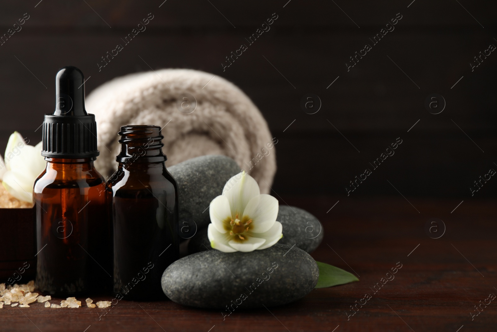 Photo of Composition with spa stones and aroma oil on wooden table, space for text