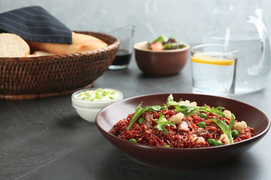 Photo of Tasty brown rice with meat and vegetables served on dark grey table