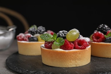 Delicious tartlets with berries on slate board, closeup