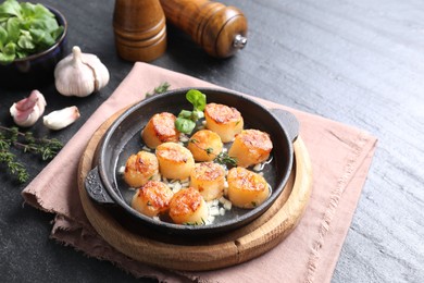 Photo of Delicious fried scallops in dish and ingredients on dark gray textured table