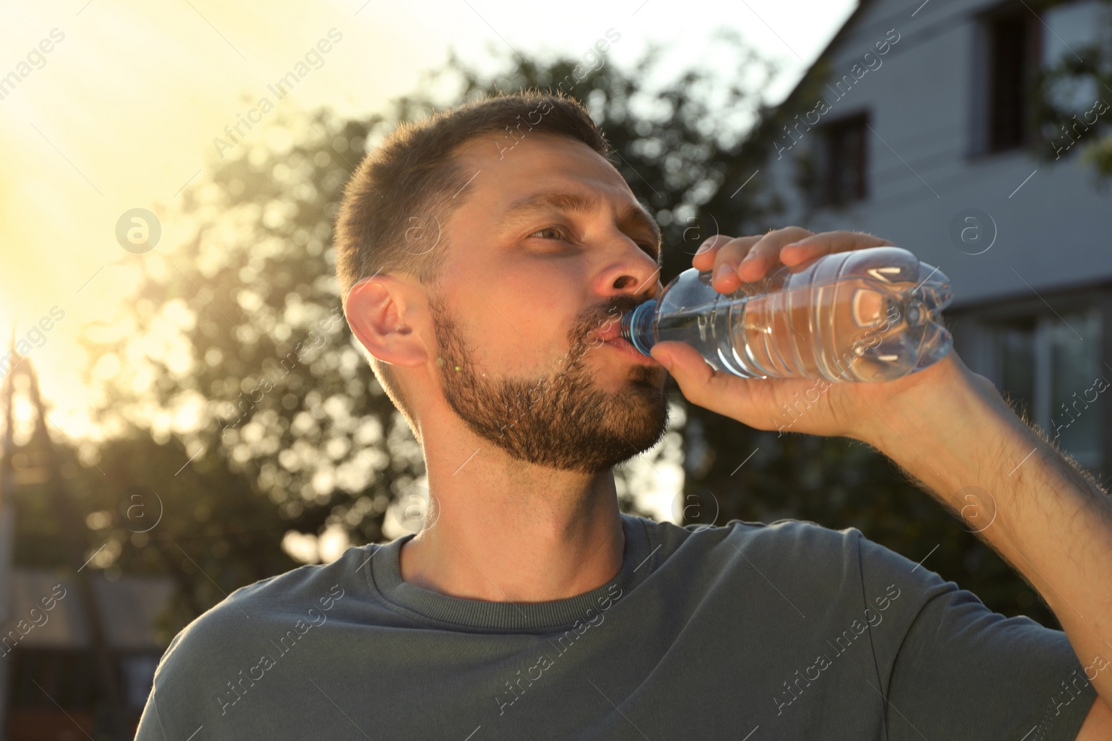 Photo of Man drinking water outdoors on hot summer day. Refreshing drink