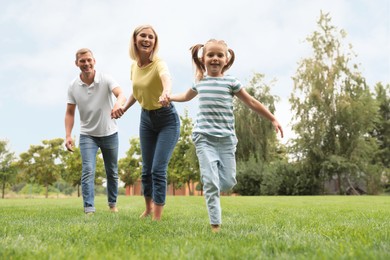 Photo of Happy family running in park on summer day