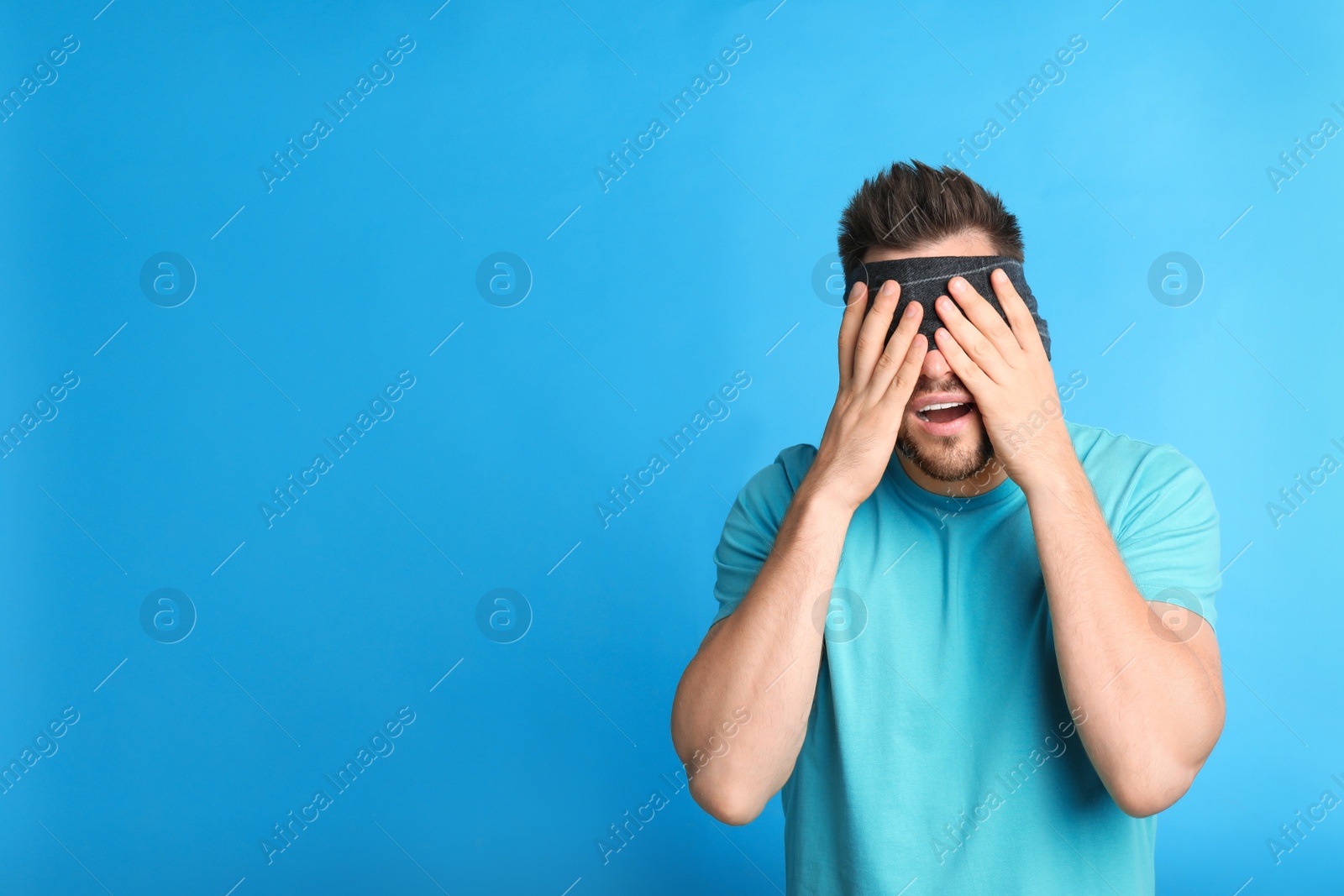 Photo of Man with black blindfold on blue background, space for text