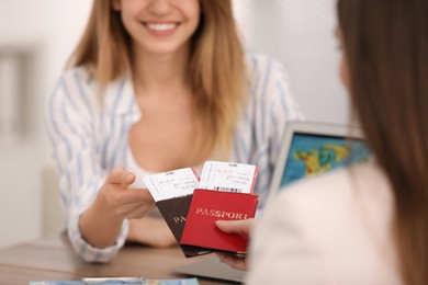 Photo of Travel agent giving tickets and passports to client in office, closeup