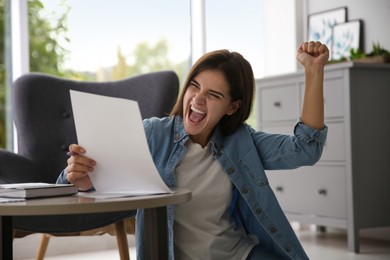 Excited woman reading paper letter at home