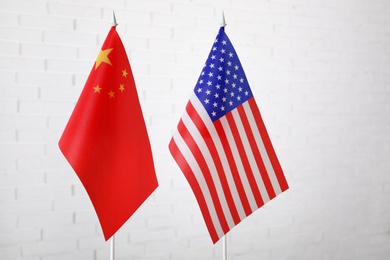 Photo of USA and China flags against white brick wall. International relations