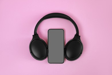 Photo of Modern wireless headphones and smartphone on pink background, top view