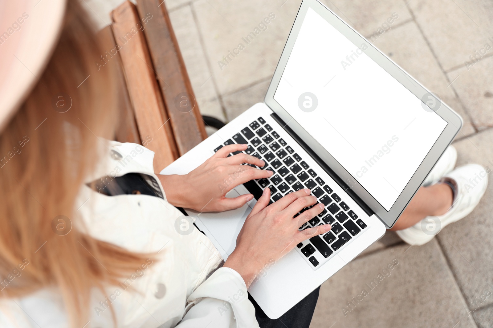 Photo of Woman using laptop on bench in city, above view