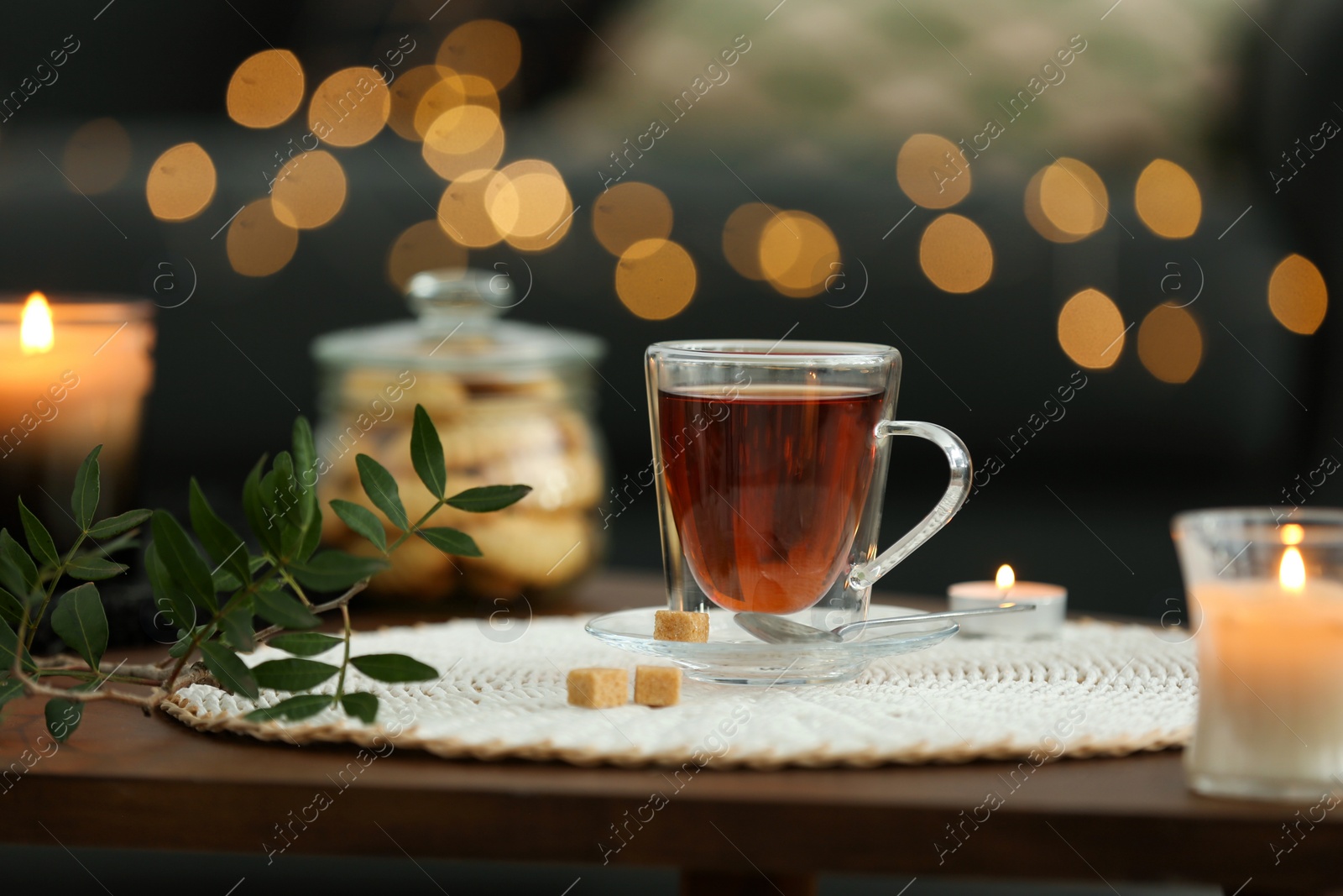 Photo of Tea, cookies and decorative elements on wooden table against blurred lights indoors