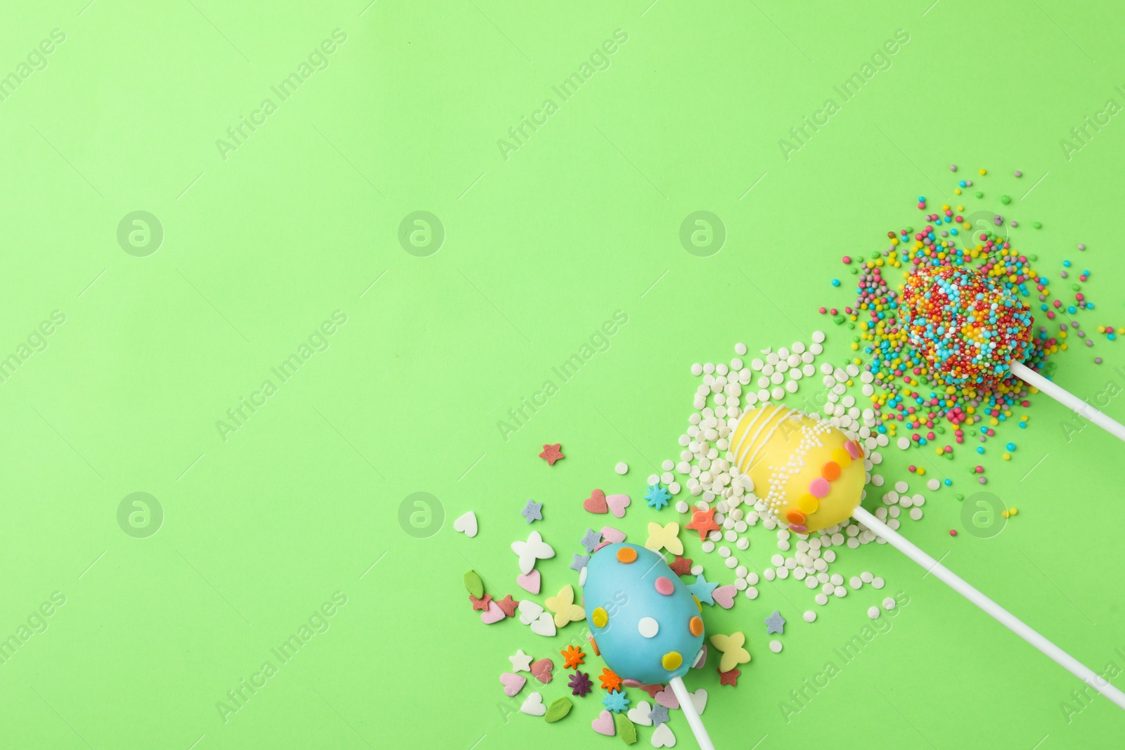 Photo of Egg shaped cake pops and space for text on green background, flat lay. Easter celebration