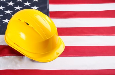 Yellow protective hard hat on American flag. Space for text