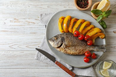 Delicious roasted dorado fish served with vegetables on wooden table, flat lay. Space for text