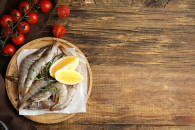 Photo of Flat lay composition with raw shrimps on wooden table. Space for text