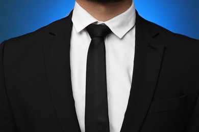 Photo of Businessman in suit and necktie on blue background, closeup